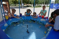 Дети ловят игрушечную рыбу в аттракционе у Южного сквера