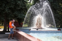Папа поднимает дочку на фонтан в парке Победы