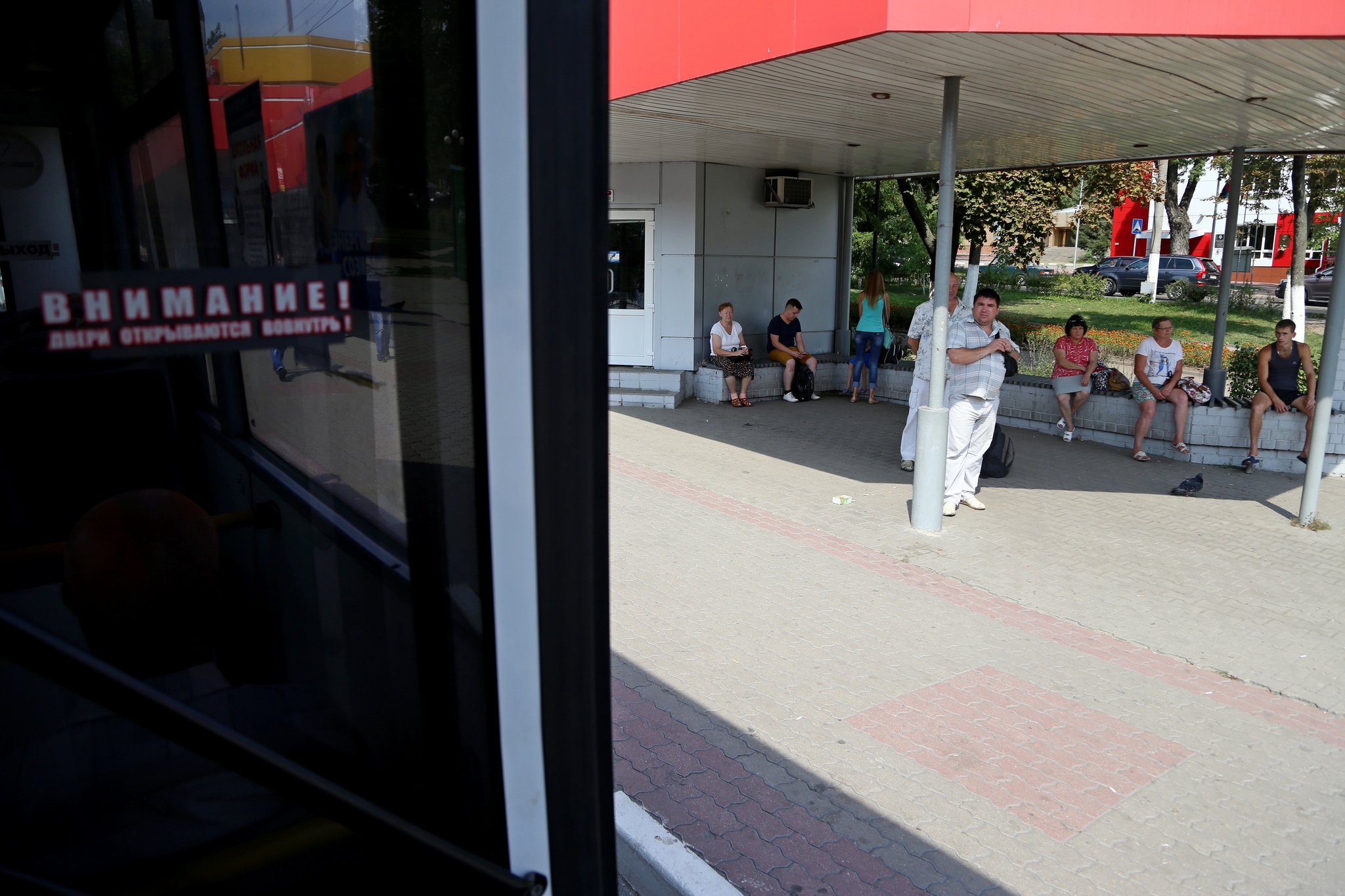 Люди ждут автобус в тени на остановке «Энергомаш»