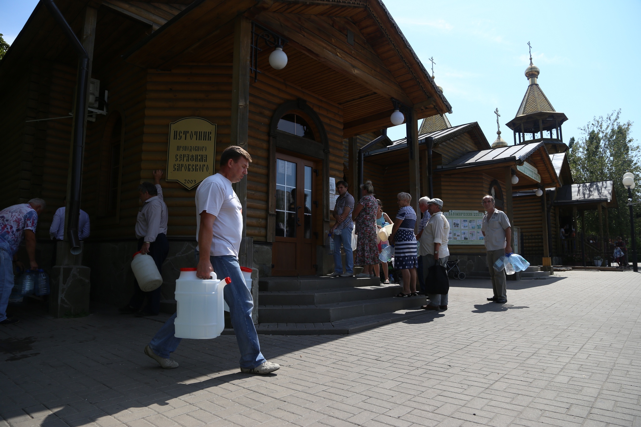 Мужчина несёт воду из храма на пересечении улиц Щорса и Королёва